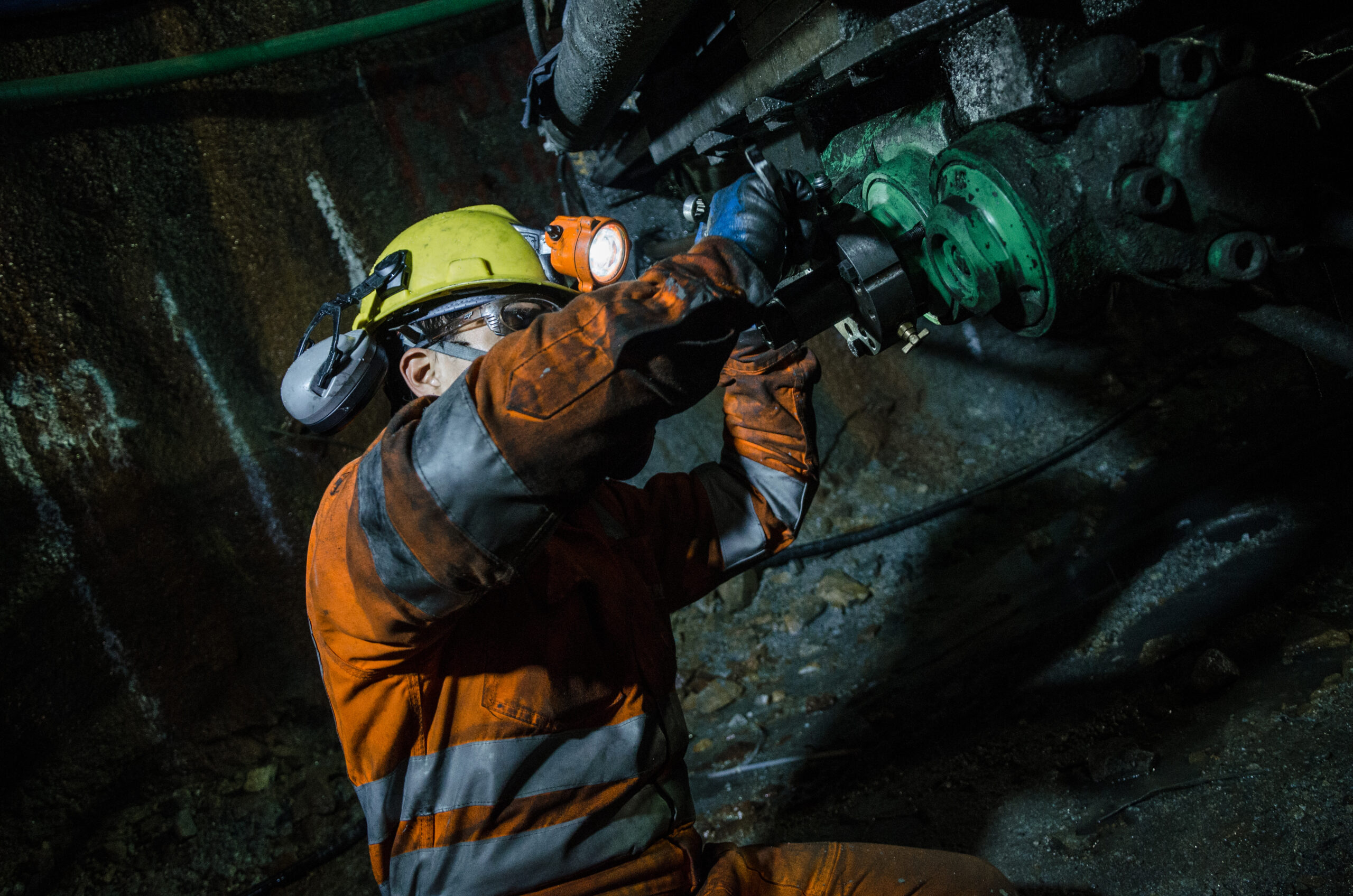 Mine worker adjusting a component on a piece of equipment during a mining operation