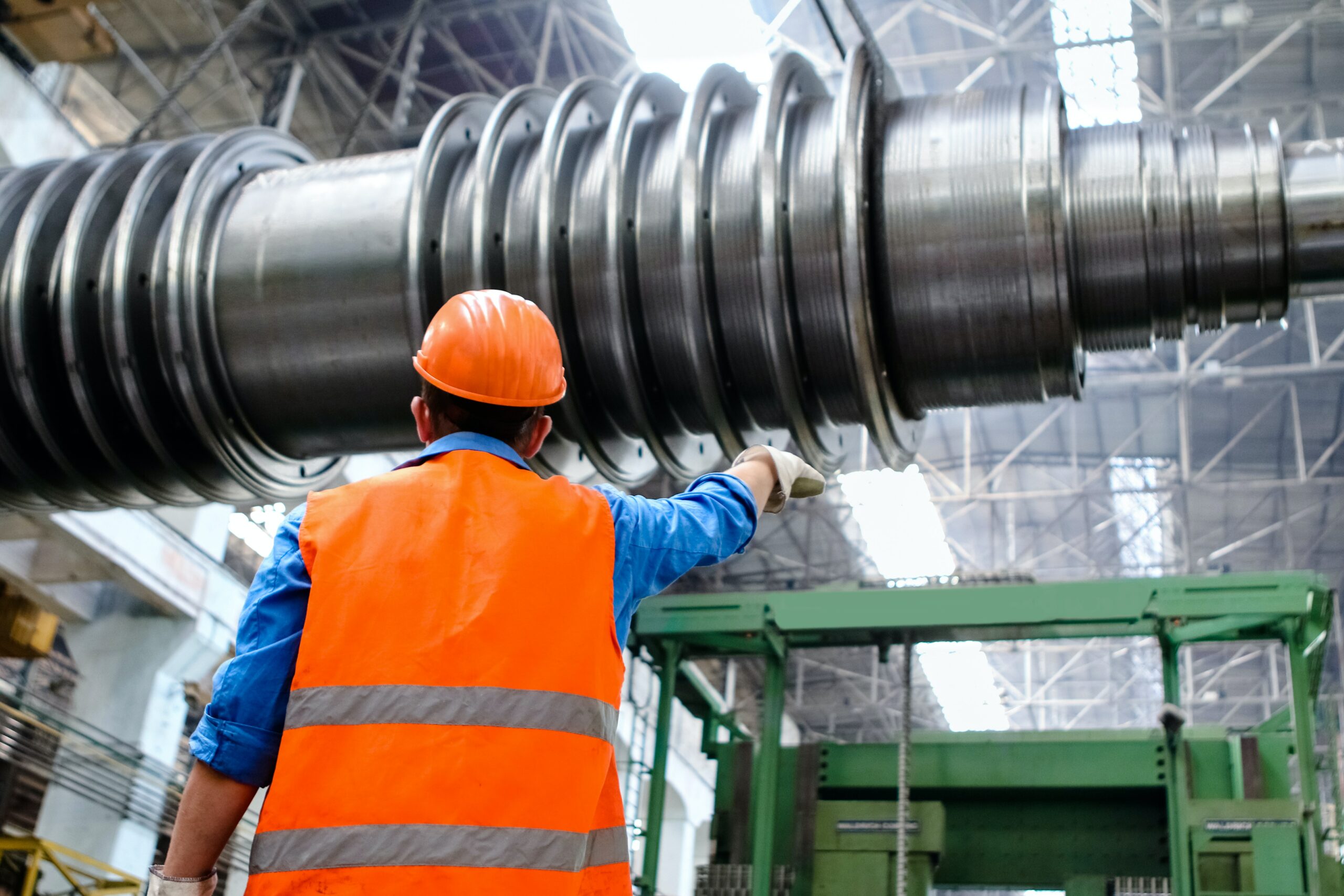 Plant employee standing in front of coupling shaft wearing PPE.