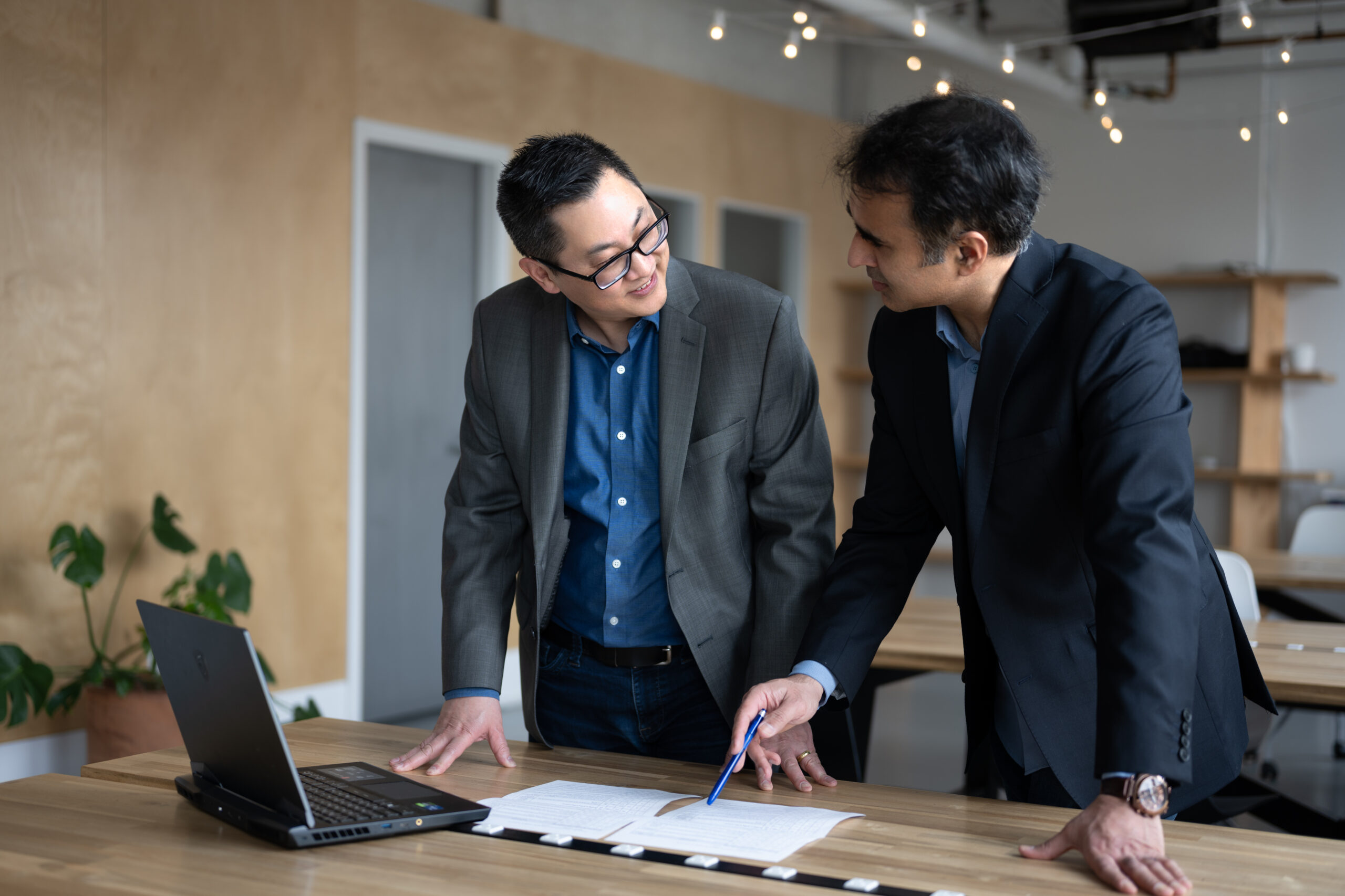 Two colleagues working together discussing something on a report or project they're working on. They seem pleasant, as they smile at one another.