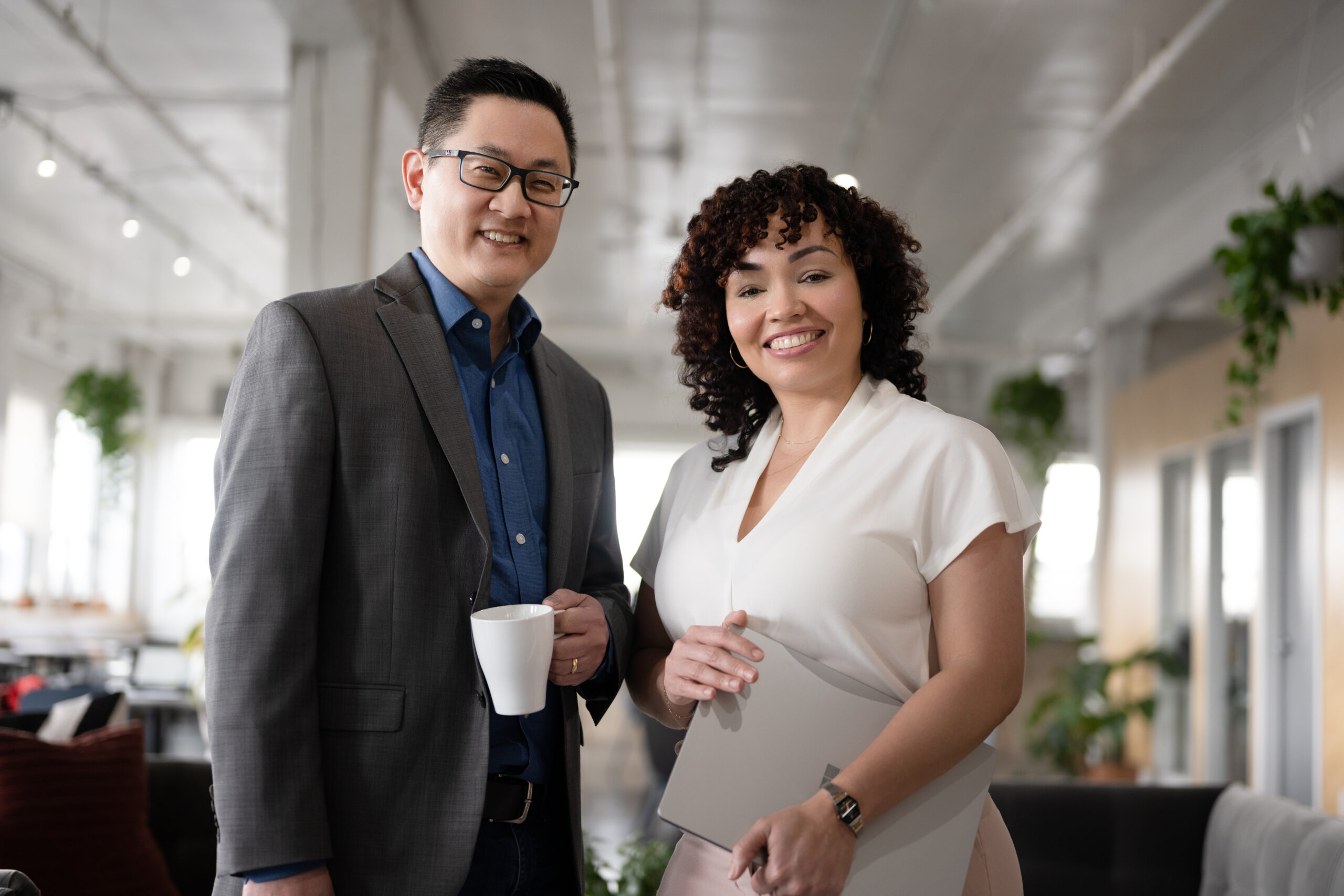 Two employees posing for a pic in the office, while seemingly having an informal meeting.