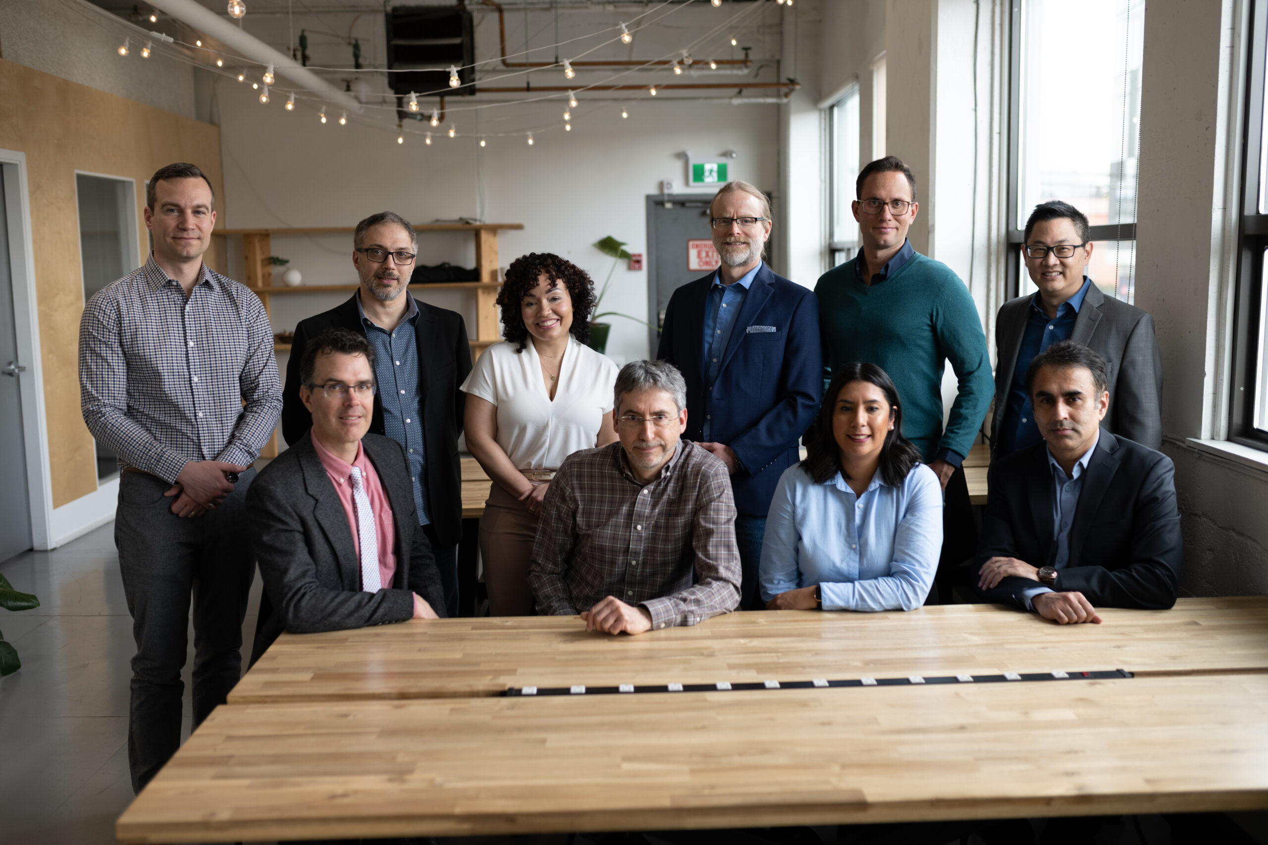 Group of SysEne employees posing for a team shot. Everyone is dressed smart and looking pleasant.